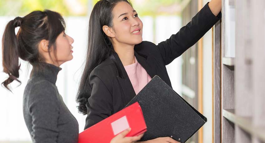 Deux femmes dans un bureau placent des dossiers sur une tablette. 